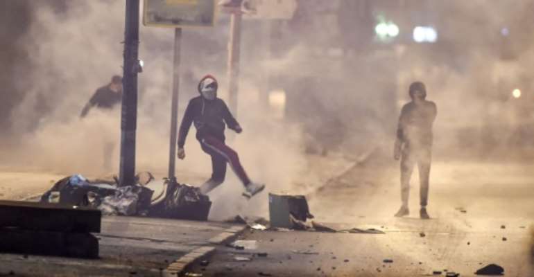 Tunisian protesters defy lockdown orders as they clash with security forces in the Ettadhamen suburb of Tunis. By FETHI BELAID (AFP)