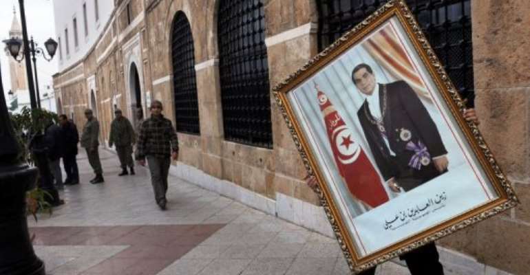 An employee at the prime minister's office removes a portrait of president Ben Ali last January after he fled into exile. By Fethi Belaid (AFP/File)
