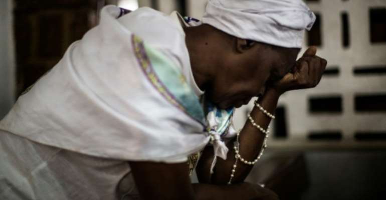 Une femme catholique prie dans une église à Libreville, le 28 août 2016. By MARCO LONGARI (AFP)
