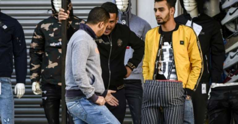 Unemployed young men gather outside a clothes store in the central Tunisian town of Sidi Bouzid -- jobs are still scarce in the cradle of the revolution and across the country, a decade on. By FETHI BELAID (AFP)
