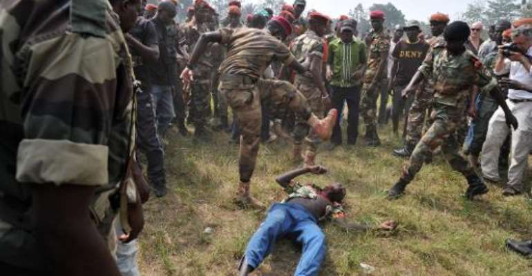 Members of the Central African Armed Forces (FACA) lynch a man suspected of being a former Seleka rebel on February 5, 2014, in Bangui. By Issouf Sanogo (AFP)