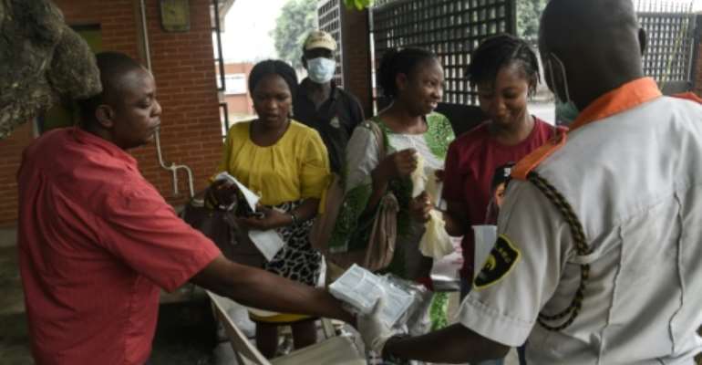 Visitors to a state hospital in Lagos collect facemasks and gloves and have their hands sanitised. By PIUS UTOMI EKPEI (AFP)