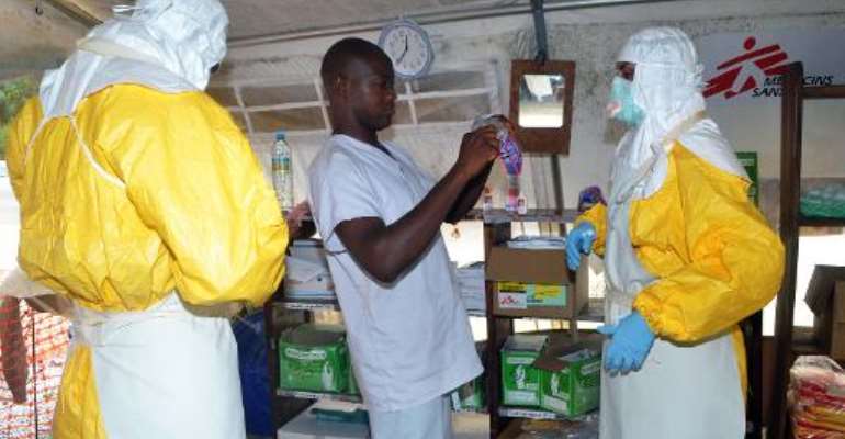 Members of Doctors Without Borders (MSF) put on protective gear at the isolation ward of the Donka Hospital in Guinea's capital Conakry on July 23, 2014. By Celou Binani (AFP/File)