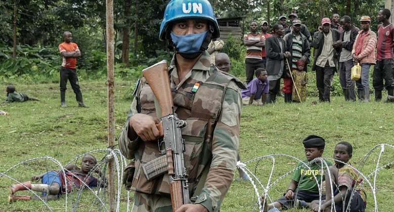 A peacekeeper protects civilians who fled violent clashes between the army and the ex-rebels of the amp;quot;M23amp;quot; in eastern DRC in January 2022.  - Source: Photo by Glody MurhabaziAFP via GettyImages