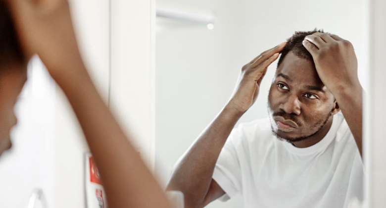 Man checking hair loss in mirror - clevelandclinic.org