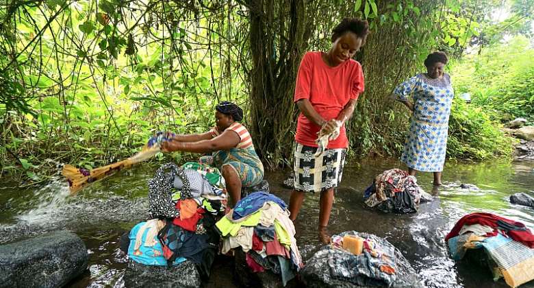 Women displaced from rural villages in the Anglophone region gather to wash clothes in a stream.  - Source: Photo by Giles ClarkeUNOCHA via Getty Images