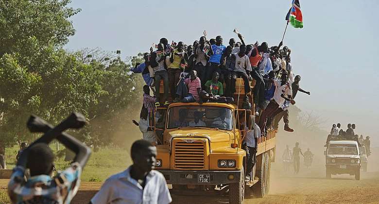 Residents hang from a bus and hold a South Sudanese flag in the disputed Abyei region of Sudan. - Source: ALI NGETHIAFP via Getty Images