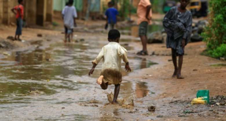 A boy runs through floodwater after a downpour in Sudan's capital Khartoum on August 13, 2022.  By ASHRAF SHAZLY AFP