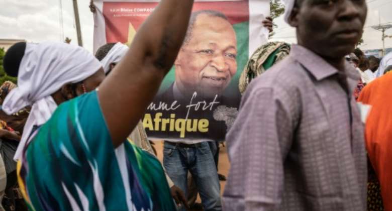 A man holds a poster depicting Blaise Compaore, former president of Burkina Faso, in front of Ouagadougou airport just before his return from eight years in exile.  By Olympia DE MAISMONT AFP