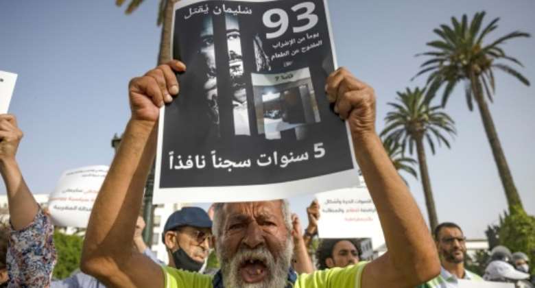 A Moroccan activist holds a poster with the image of journalist Soulaimane Raissouni, during a rally by his supporters after a court sentenced him to five years in prison for sexual assault.  By FADEL SENNA AFPFile