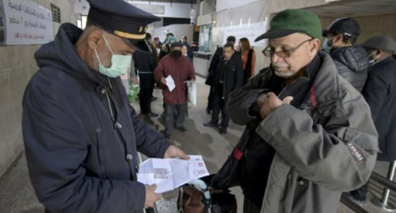 A public transport employee checks a passenger's vaccination pass at a railway station in Tunis.  By FETHI BELAID (AFP)