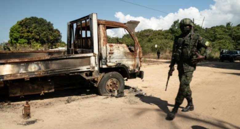 A Rwandan soldier walks past a burned-out truck in Cabo Delgado's capital Palma last September.  By Simon WOHLFAHRT AFP