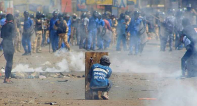 A Sudanese protester takes cover on Thursday from tear gas fired by security forces amid clashes in the Khartoum Bahri twin city of the Sudanese capital.  By - AFPFile