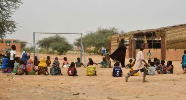 A teacher and her pupils play in a yard at a school near a site for displaced people on the outskirts of Ouallam, Niger in October 2022.  By BOUREIMA HAMA AFPFile