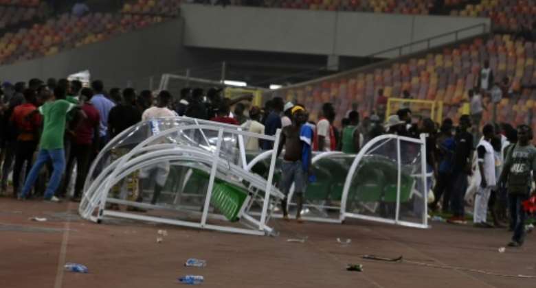 Angry football fans break a players' bench in Abuja after Nigeria lost to Ghana in a 2022 World Cup play-off.  By PIUS UTOMI EKPEI AFP