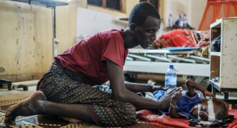 'Forced to choose between their children and their livestock': Herder Abdullahi Gorane tends to his malnourished son in Gode General Hospital.  By EDUARDO SOTERAS AFP