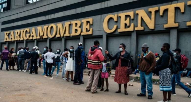 Greenback shortage: People in Harare line up to withdraw US dollars on Christmas Eve. Some were so desperate for hard currency that they even slept in the queue to keep their place.  By Jekesai NJIKIZANA AFP