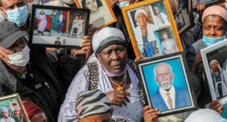 Israelis from the Ethiopian community hold photographs of their relatives during a demonstration demanding the rescue of their relatives left behind amidst the conflict in Ethiopia, outside the Prime Minister's office in Jerusalem. By AHMAD GHARABLI (AFP)