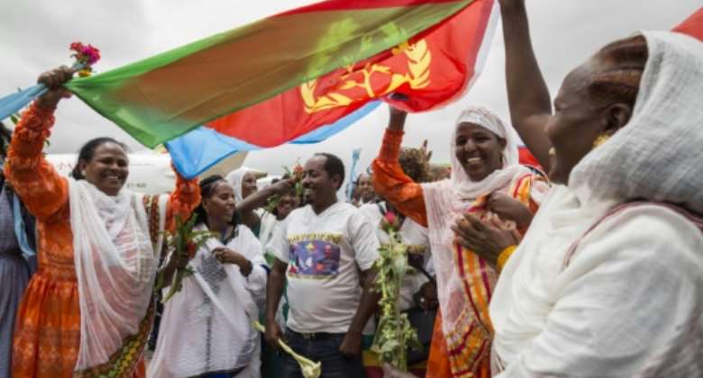 Joy: Eritrean women hold aloft the national flag in July 2018 to welcome passengers arriving from Ethiopia, a key step in the two rivals' path to peace.  By MICHAEL TEWELDE AFPFile