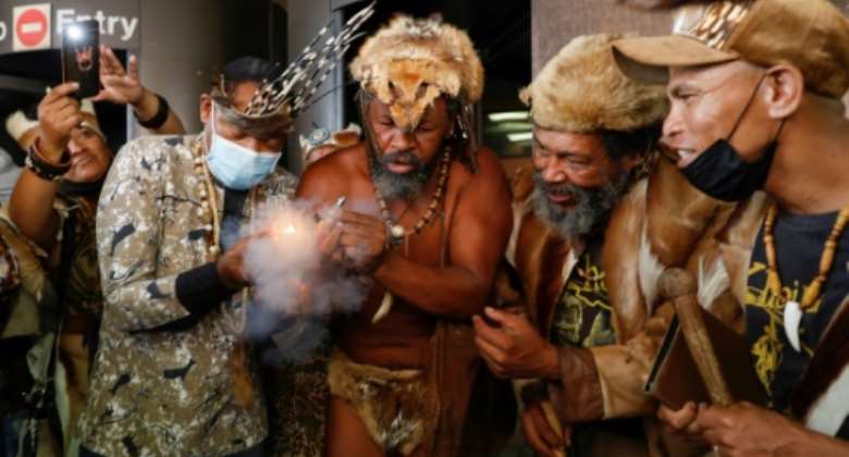 King Khoisan South Africa, second from the left, takes a puff after leaving the courtroom in Pretoria.  By Phill Magakoe AFP