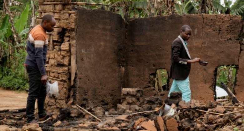 Mukondi's village chief Deogratias Kasereka R searches the remains of a house burned down during an attack attributed to the ADF.  By Joel Bibuya AFP