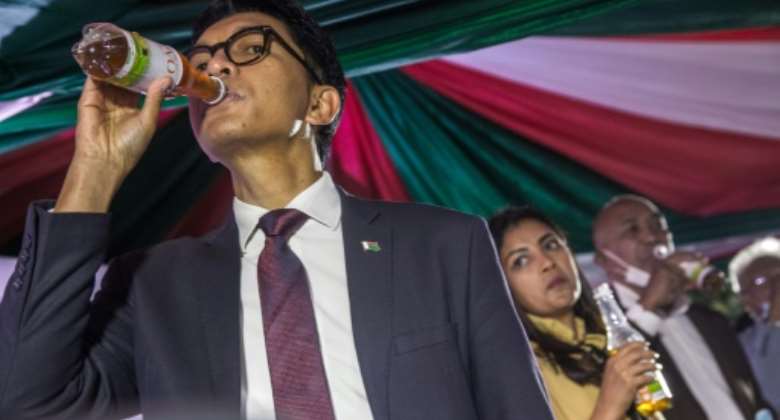 Presidential push: Madagascan leader Andry Rajoelina drinks from a bottle of Covid Organics, a claimed cure for coronavirus, at the product's launch on April 20. Scientists say there is no evidence to support the claims.  By RIJASOLO AFP