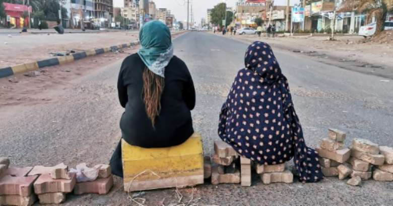 Sudanese women sit atop a brick barricade at 60th Street on January 18, 2022 in the capital Khartoum as part of a civil disobedience campaign following the killing of seven anti-coup demonstrators.  By - AFP