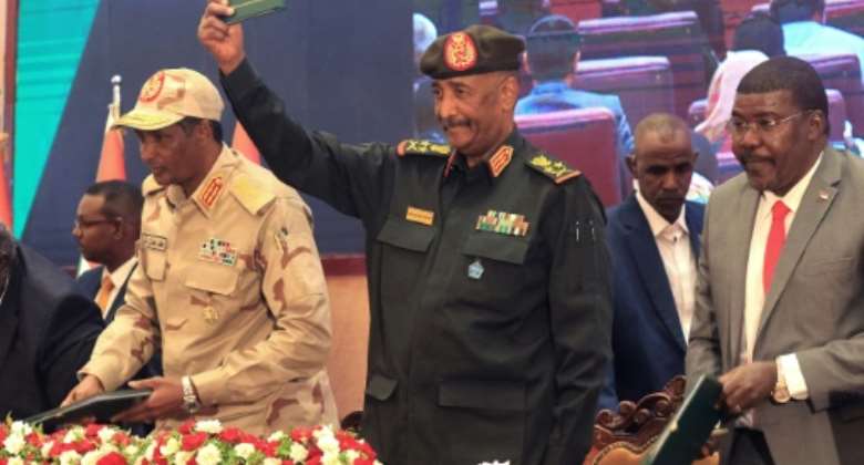 Sudan's Army chief Abdel Fattah al-Burhan center and paramilitary commander Mohamed Hamdan Dagalo left lift documents alongside civilian leaders following the signing of an initial transition deal on December 5, 2022.  By ASHRAF SHAZLY AFP