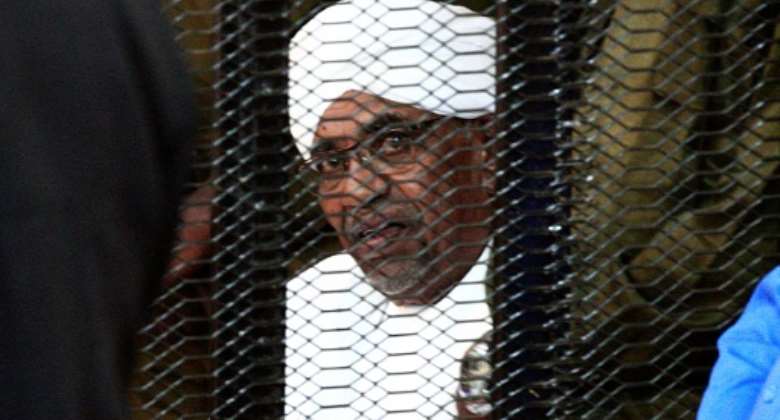 Sudan's deposed president Omar al-Bashir looks on from a defendant's cage during the opening of his corruption trial in Khartoum on August 19, 2019.  By Ebrahim HAMID AFPFile