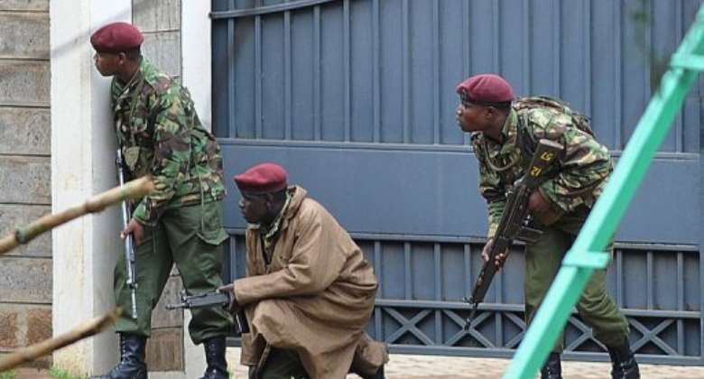 Armed Kenyan policemen take cover outside the Westgate mall in Nairobi on September 23, 2013.  By Simon Maina AFP
