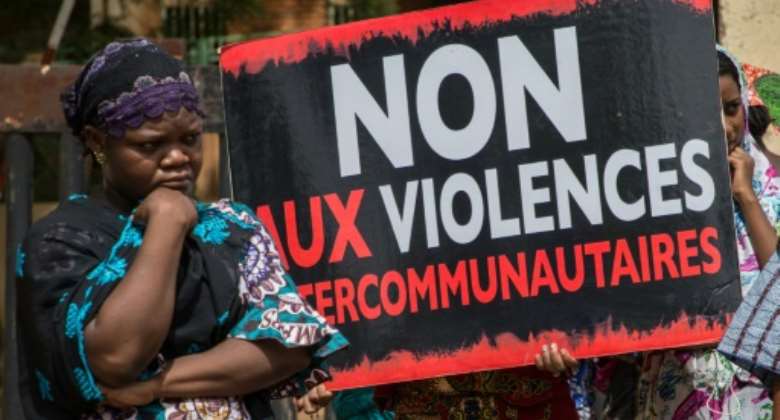 Women hold a sign reading 'No to intercommunity violence' after Fulani villagers in northern Burkina Faso were massacred in 2019 reprisal for a jihadist attack.  By OLYMPIA DE MAISMONT AFP