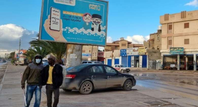 Workers in Libya's capital Tripoli pass an electoral billboard reading in Arabic, 'Register and vote before missing your chance' -- but a postponement of the ballot is widely expected.  By Mahmud TURKIA (AFP/File)