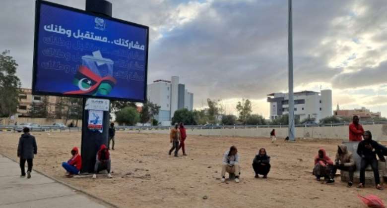 Workers sit near an electoral billboard reading in Arabic 