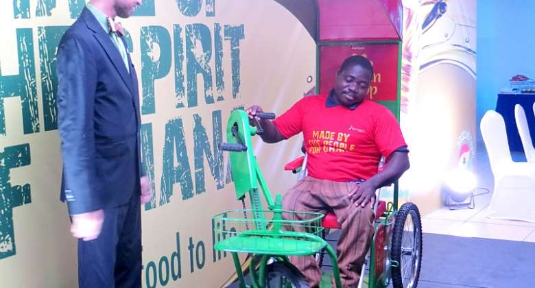 CEO of Avnash Industries Ghana Limited, Mr. Jai Mirchandani, Looks On As One of Disabled Persons Demonstrate The Use Of The Tricycle