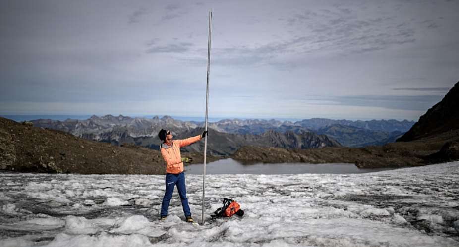 Matthias Huss with a four-metre-long measuring stake indicating the amount of ice that melted over the past year on the Scex. Rouge glacier -  Fabrice COFFRINI / AFP