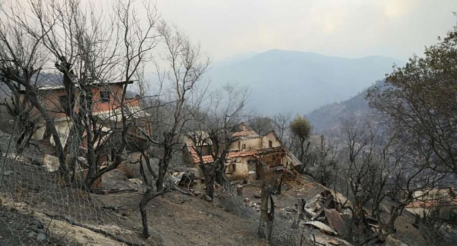 Damaged buildings are seen on a scorched hill after a forest fire swept through the area in Bordj Thar, a town and commune in Algerias northeastern Jijel Province, on August 27, 2026. Algerian President Abdelmadjid Tebboune on August 27 declared a three