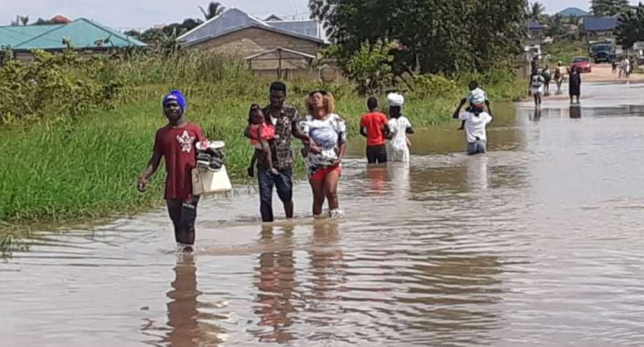 Residents of Peace Town, in Amanfro walk through the flood