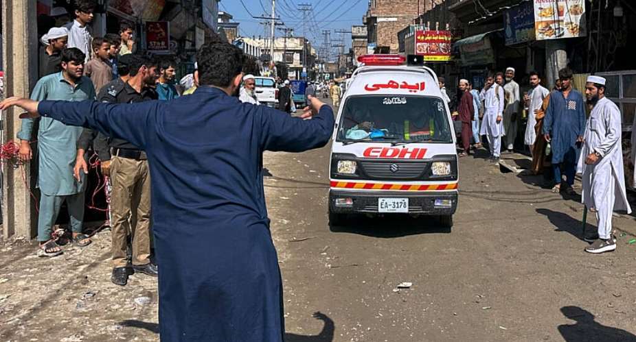 A volunteer clears the way for an ambulance transporting injured school children following a roof collapse at a private school in Peshawar, Pakistan, on October 15, 2026. -  Maaz Awan, AP
