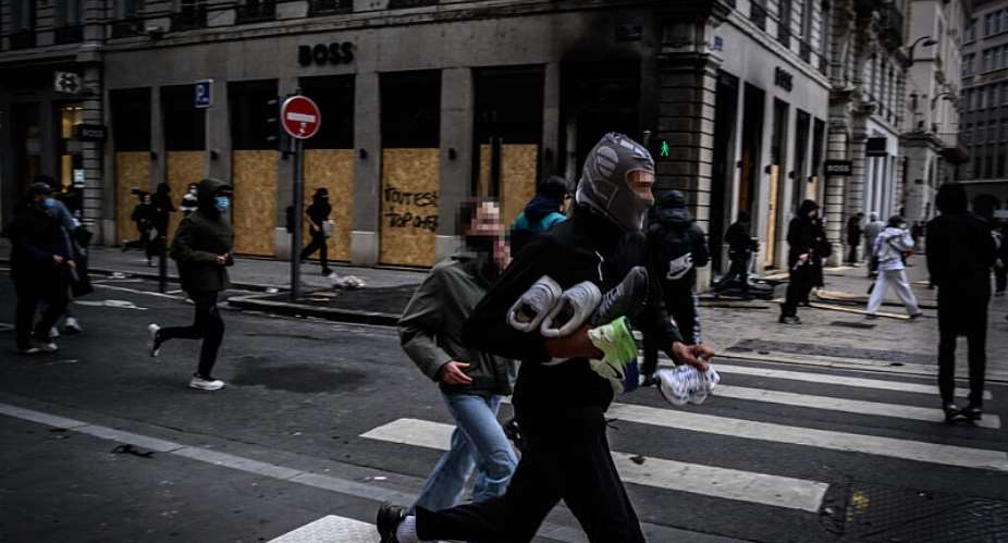 A looter runs off with his haul in Lyon, France’s third biggest city, on October 17, 2026. -  Jeff Pachoud, AFP