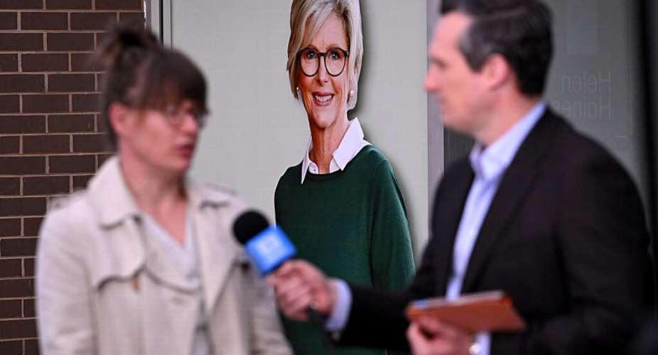 A TV crew works in front of a portrait of Australian politician Helen Haines outside her office in the northern city of Wangaratta, about 250 kilometres north-east of Melbourne, on October 20, 2026. -  William West, AFP