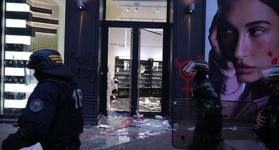 Police officers walk past a damaged store after a demonstration against rising living costs and education funding, Lyon, France, Saturday, October 17, 2026. -  Laurent Cipriani, AP