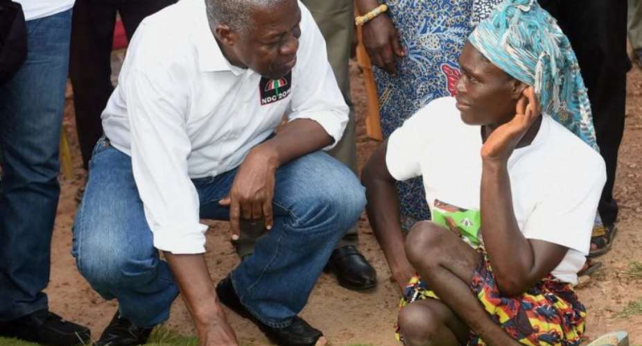 Vice President Kwesi Bekoe Amissah-Arthur squatting beside a woman with physical disability