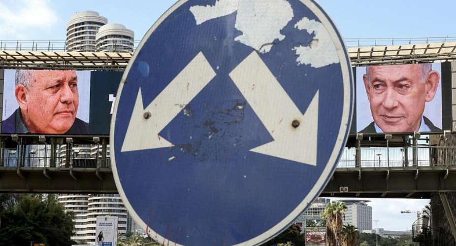 A road sign stands in front of a large billboard featuring Israeli Prime Minister Benjamin Netanyahu (R) of the Likud party and former military chief and leader of the centrist Yashar party Gadi Eisenkot in Ramat Gan on October 20, 2026. -  Jack Guez, AFP