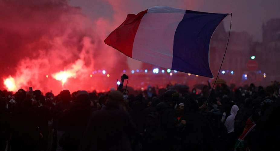 Protesters hold a French flag amid clashes during demonstration organised by labour unions in Paris as part of nationwide protests called by the Yellow Vests movement joined by French high school and university students against the cost of living and rising fuel prices, in France, October 24, 2026. -  Abdul Saboor / Reuters