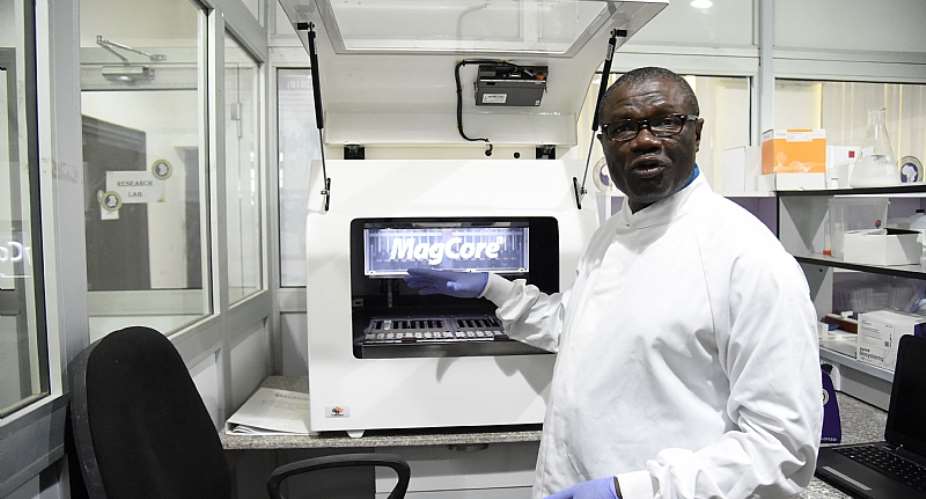 Professor Christian Happi, director of the African Centre of Excellence for Genomics of Infectious Diseases, displays one of the most advanced automated acid extractors being used in the laboratory.  - Source: Pius Utomi EkpeiAFP via Getty Images
