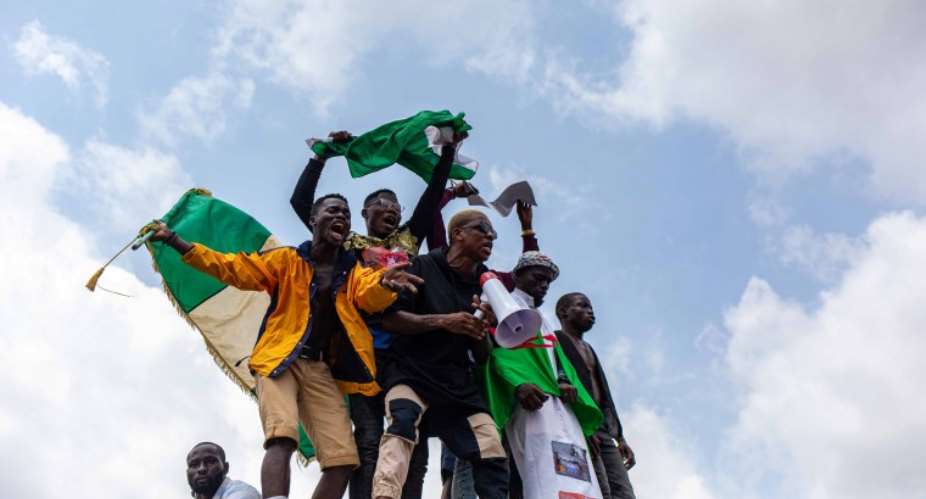 Nigerian youths seen waving the Nigerian national flag in front of a crowd in support of the ongoing protest against the unjust brutality of The Nigerian Police Force Unit named Special Anti-Robbery Squad SARS in Lagos on October 13, 2020. Journalists have been attacked by law enforcement and unidentified assailants during the protests. AFPBenson Ibeabuchi
