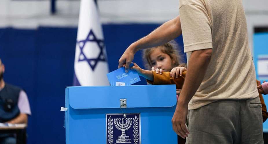 An Israeli man, accompanied by children, votes at a polling station during Israels national election, in Jerusalem, 27 October 2026. - REUTERS - Ronen Zvulun
