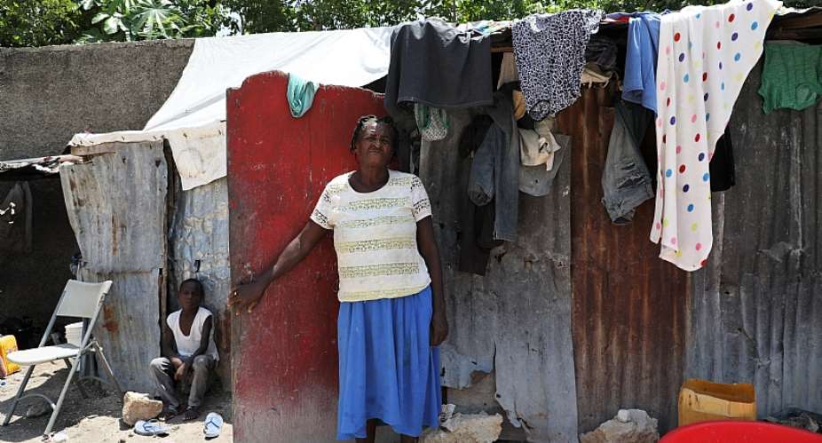 A woman stands in front of her home at a displacement site in Port-au-Prince, Haiti. Photo: IOM.