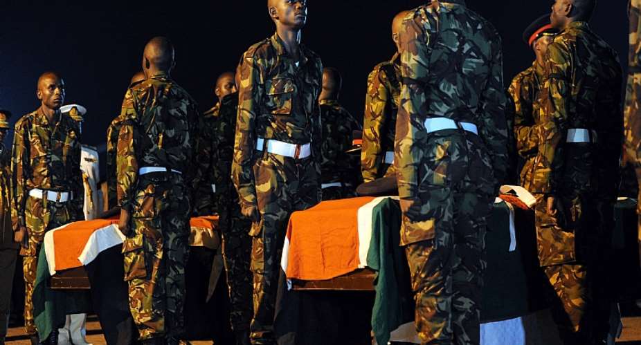 Kenyan soldiers stand over caskets bearing the remains of their fallen comrades during prayers in 2016. - Source: Tony KarumbaAFP via Getty Images