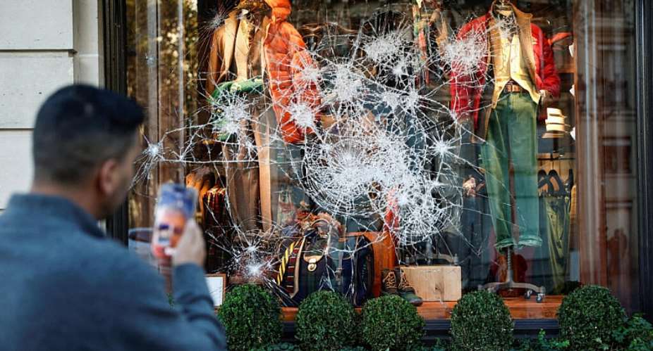 A man takes photos of a vandalised Ralph Lauren storefront a day after clashes during a national day of demonstrations against the cost of living and rising fuel prices, in Paris, France, October 18, 2026. -  Benoit Tessier, Reuters
